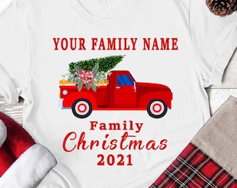 May include: White t-shirt with a red truck carrying a Christmas tree. The text "YOUR FAMILY NAME" and "Family Christmas 2021" is printed on the shirt.