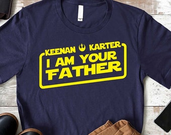 May include: A navy blue t-shirt with a yellow graphic that says "Keenan Karter I Am Your Father" in a Star Wars inspired font.