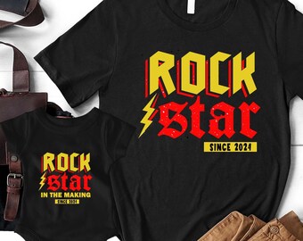 May include: Two black t-shirts with a rock star design. The larger shirt says "Rock Star Since 2024". The smaller shirt says "Rock Star In The Making Since 2024".
