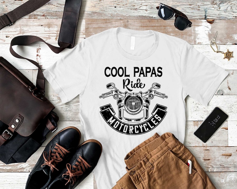 May include: White t-shirt with a black and white graphic of a motorcycle and the text "Cool Papas Ride Motorcycles".