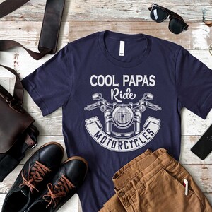 May include: A navy blue t-shirt with a white graphic of a motorcycle and the text "Cool Papas Ride Motorcycles".