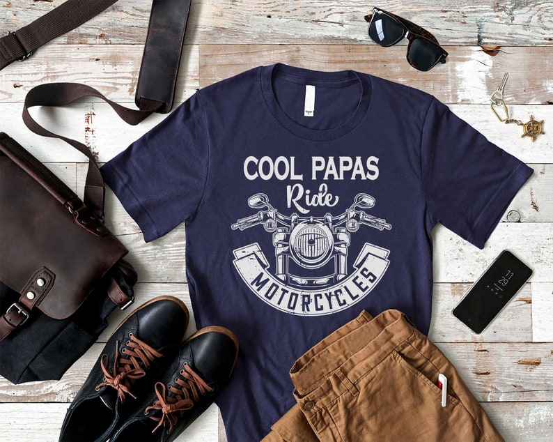 May include: A navy blue t-shirt with a white graphic of a motorcycle and the text "Cool Papas Ride Motorcycles".