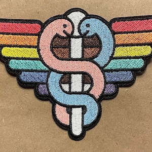 May include: A rainbow-colored embroidered patch featuring a stylized caduceus, a symbol of medicine, with two snakes intertwined around a staff. The snakes are pink and blue, and the staff is white.