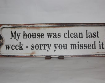 May include: A white rectangular sign with a distressed, rusty brown border. The sign reads "My house was clean last week - sorry you missed it."