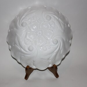 May include: White milk glass bowl with a swirl design. The bowl is on a wooden stand.