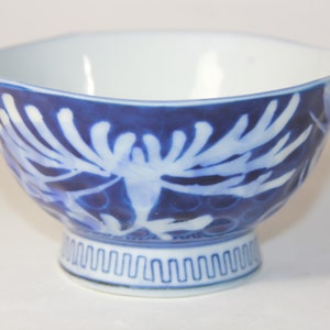 May include: A small, white ceramic bowl with a blue and white floral design. The bowl has a scalloped rim and a footed base.