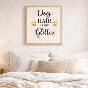 Puede incluir: Un cuadro cuadrado en un marco de madera clara con el texto negro Dog HAIR is my Glitter sobre un fondo blanco, decorado con huellas de patas doradas y peque&ntilde;as estrellas dispersas alrededor de las letras.