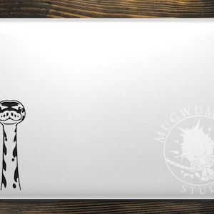 May include: Black and white sticker of a snake's head and neck on a silver laptop. The sticker is on the left side of the laptop. On the right side of the laptop is a white sticker of a logo that says "Mugwump Studios".