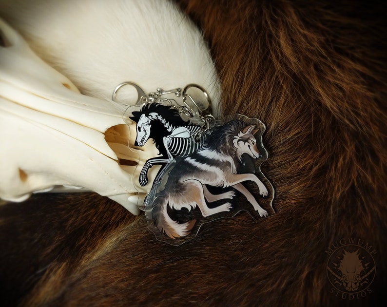 Peut inclure: Un porte-cl&eacute;s argent&eacute; avec un charme de squelette de loup noir et blanc et un charme de loup brun et blanc. Les charmes sont attach&eacute;s &agrave; une cha&icirc;ne argent&eacute;e avec un anneau argent&eacute;.