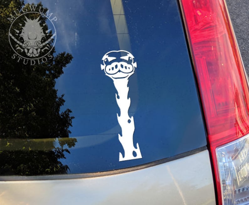 May include: White vinyl sticker of a cartoon giraffe with a long neck and a goofy expression. The sticker is on the back window of a silver car.