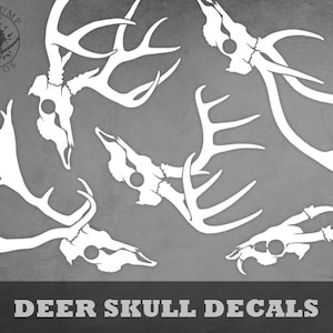 May include: Five white deer skull decals with antlers. The decals are on a gray background. The text "DEER SKULL DECALS" is at the bottom of the image.