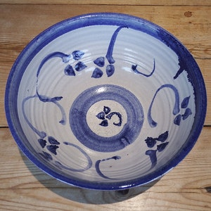 May include: A white ceramic bowl with a blue rim and blue floral designs. The bowl has a white glaze and a blue floral pattern.