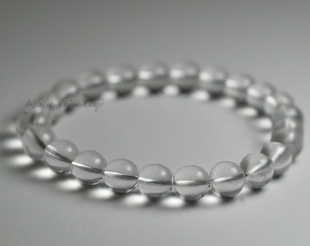 Peut inclure: Un bracelet en perles de cristal de roche clair. Le bracelet est composé de perles rondes et lisses qui sont enfilées sur un cordon élastique transparent.
