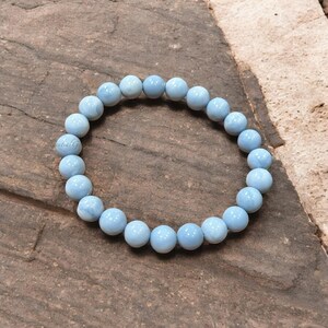 Peut inclure: Un bracelet en pierre précieuse bleu clair avec des perles rondes. Le bracelet est fait d'opale naturelle et mesure environ 20 cm de long.