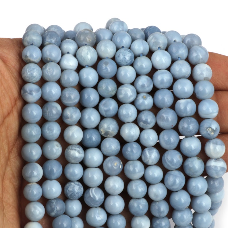 May include: A strand of light blue opal beads. The beads are round and smooth, with a slightly iridescent finish.