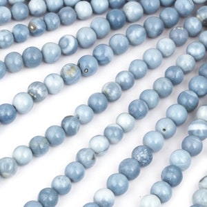 May include: A strand of light blue opal beads, each bead is round and smooth. The beads are arranged in rows, creating a pattern of overlapping circles.