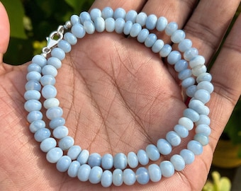 Op de afbeelding: Een delicate ketting met twee strengen lichtblauwe edelsteen kralen. De kralen zijn ovaal en verbonden met een zilveren sluiting. De ketting wordt getoond tegen een neutrale achtergrond, die de zachte blauwe kleur van de stenen benadrukt.