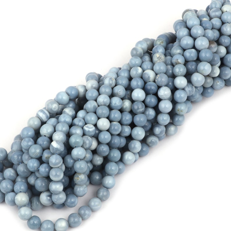 May include: A strand of light blue opal beads. The beads are round and smooth, with a slightly iridescent finish.