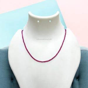 Puede incluir: Un collar hecho de pequeñas cuentas de rubí facetadas. El collar se muestra en un busto de maniquí blanco. El texto "InfluentialGemsCraft" es visible en el busto.