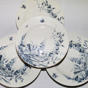 May include: Set of four white ceramic plates with blue floral designs. The plates feature a delicate floral pattern with blue leaves and flowers.