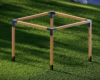 May include: A wooden frame with black metal corner brackets. The frame is standing on a green grassy surface.
