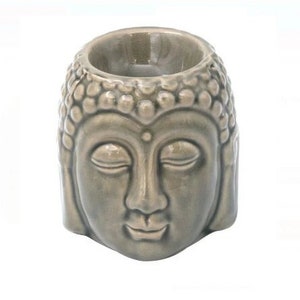 Puede incluir: Un quemador de aceite de cerámica gris en forma de cabeza de Buda. El quemador tiene un pequeño pozo en la parte superior para contener aceite esencial y una vela de té.