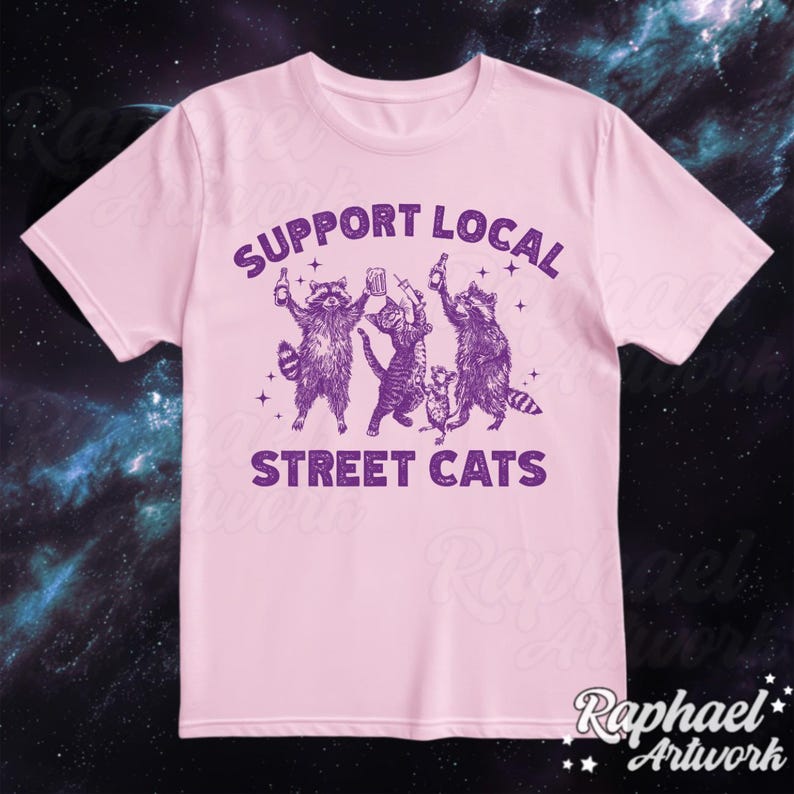 May include: Pink t-shirt with a purple graphic of raccoons and cats drinking beer. The text "Support Local Street Cats" is printed on the shirt.