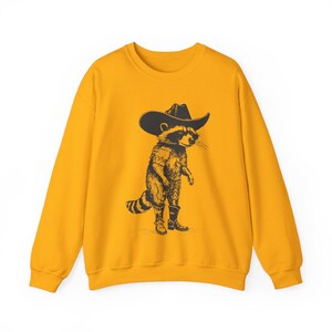 May include: A yellow sweatshirt with a black and white illustration of a raccoon wearing a cowboy hat and boots.