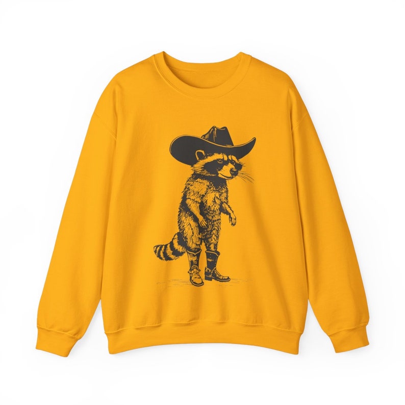 May include: A yellow sweatshirt with a black and white illustration of a raccoon wearing a cowboy hat and boots.