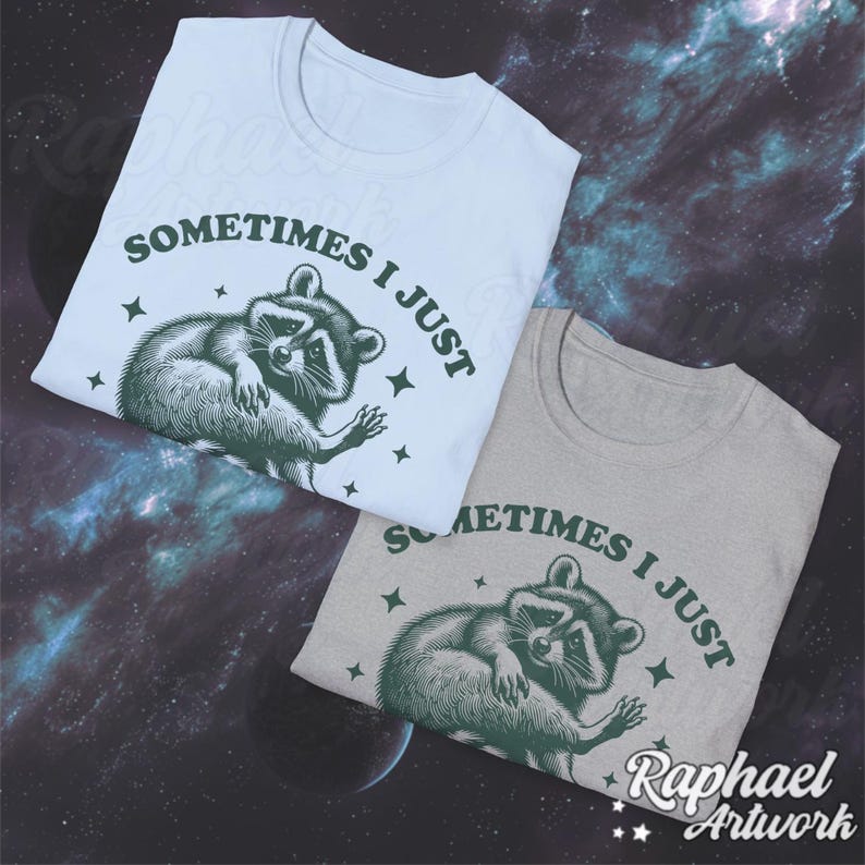 Pode incluir: Duas camisetas com um gr&aacute;fico de guaxinim e o texto "Sometimes I just" em letras verdes. As camisetas s&atilde;o azul claro e cinza.