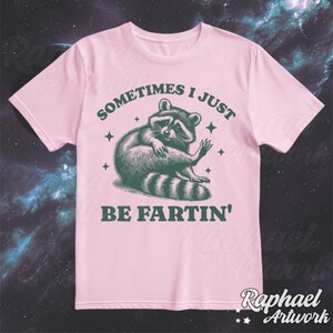 Pode incluir: Camiseta rosa com um gr&aacute;fico de guaxinim verde e o texto "Sometimes I Just Be Fartin'" impresso nela.