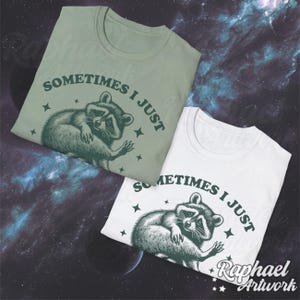Pode incluir: Duas camisetas com um gr&aacute;fico de guaxinim verde e o texto "Sometimes I just" impresso nelas. As camisetas s&atilde;o de cores diferentes, uma &eacute; verde e a outra &eacute; branca.