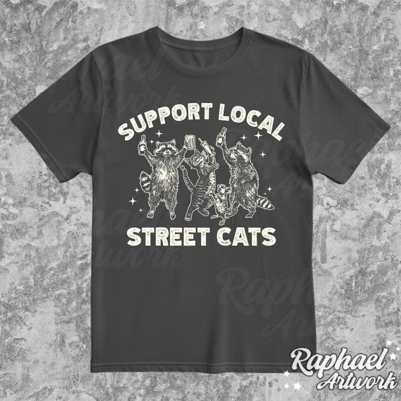 May include: A dark gray t-shirt with a white graphic of four raccoons holding drinks and the text "Support Local Street Cats".