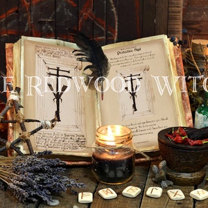May include: An open book with illustrations and text, a black feather, candles, herbs, and other mystical items. The text "THE REDWOOD WITCH" is displayed across the top of the image. The scene is set on a wooden surface.
