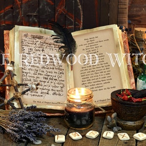May include: A still life arrangement featuring a vintage book, candles, and various mystical items. The text "THE REDWOOD WITCH" is displayed. Other items include a mortar and pestle, herbs, and rune stones, creating a witchy aesthetic.