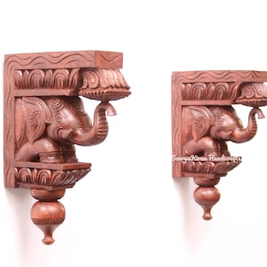 Pode incluir: Dois suportes de parede de madeira com talhas intrincadas de elefantes. Os suportes são de uma cor castanho rica e têm um design tradicional indiano.