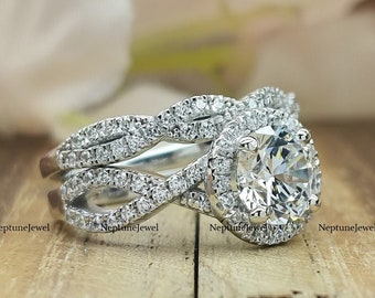 May include: A diamond engagement ring set with a round-cut center stone and a halo of smaller diamonds. The band features a twisted design, and the ring is set on a wooden surface.