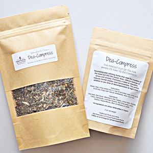 May include: Two brown paper bags with white labels that say "Dea-Compress" and contain a blend of dried herbs. The text on the label says "The perfect cup of tea for when it's time to decompress!" and lists the ingredients: Holy Basil, Red Clover, Blackberry leaves, Lemon Balm, St. John's Wort, Chamomile, Lavender flowers, Red Rose Buds, Lemon Verbena, Passionflower, Blue Cornflowers & Coltsfoot. All ingredients are either wildcrafted or organic. 3 oz net weight.