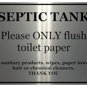 May include: A rectangular metal sign with rounded corners and a black border. The sign reads "SEPTIC TANK" at the top, followed by instructions to only flush toilet paper. Additional text prohibits other items. The sign is silver with black text.
