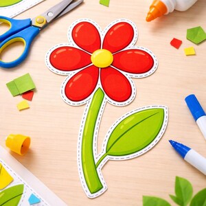 Può includere: Una scena artigianale colorata con un grande ritaglio di fiore rosso con centro giallo e stelo e foglia verdi. Forbici, colla, pennarelli e ritagli di carta sono disposti su una superficie di legno chiaro, suggerendo un progetto fai-da-te o un'attività artigianale.