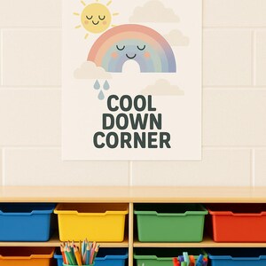 Może przedstawiać: Radosny plakat z uśmiechniętym słońcem, tęczą i chmurami, z napisem "COOL DOWN CORNER". Poniżej kolorowe pojemniki i kubki z ołówkami i markerami stoją na drewnianym stole.