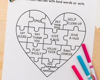 May include: A white paper with a heart-shaped puzzle graphic, featuring phrases like "Smile" and "Give a Hug." The text "Build a Caring Heart" is at the top. Crayons and markers in various colors are scattered around the paper.