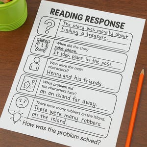 May include: A white worksheet titled "READING RESPONSE" with fill-in-the-blank questions about a story. An orange pencil and a green cup with coloured pencils are on the wooden surface.