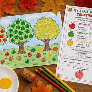 Może przedstawiać: Wydrukowany arkusz zadań zatytułowany My Apple Orchard Counting Log z rysunkiem trzech drzew z czerwonymi, zielonymi i żółtymi jabłkami, paletą farb w kolorze czerwonym, zielonym i żółtym, korkiem oraz trzema kredkami na drewnianej powierzchni.