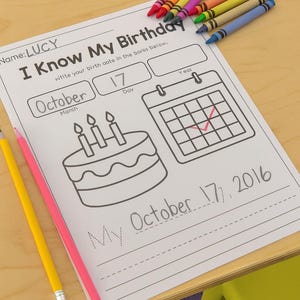 May include: A worksheet titled "I Know My Birthday" with the name "LUCY" at the top. The worksheet includes a cake, a calendar, and the date "October 17, 2016". Colorful crayons and pencils are scattered around the worksheet.