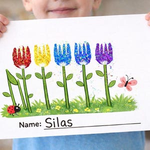 May include: A child holds a white paper with a colorful flower drawing. The flowers are made with fork imprints in red, yellow, blue, and purple. Green stems and leaves, a ladybug, and a butterfly are also present. The name "Silas" is written at the bottom.