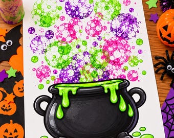 May include: A white sheet of paper featuring a black cauldron with bright green liquid dripping over the rim. Above the cauldron, there are numerous circular bubble prints in vibrant shades of neon green, purple, and hot pink, creating a bubbly effect.