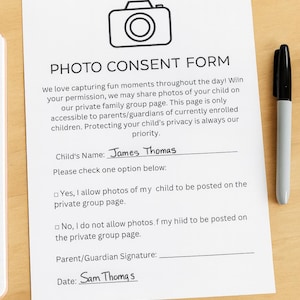 May include: A photo consent form on white paper with the title "PHOTO CONSENT FORM" and a camera icon. The form includes lines for a child's name, signature, and date. A black marker and a keyboard are in the background.