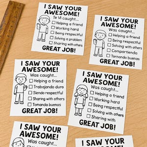 Puede incluir: Tarjetas blancas con el texto "I SAW YOUR AWESOME!" y una figura de dibujos animados. Las tarjetas tienen casillas de verificación para comportamientos positivos como "Ayudar a un amigo" y "Trabajar duro". Se ven marcadores coloridos.
