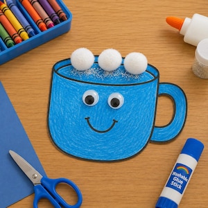 May include: A blue paper mug craft with a black outline, two googly eyes, and a black drawn smile. Three white pom-poms are attached to the top to represent marshmallows, accented with silver glitter. The mug is surrounded by crayons, glue, and scissors.